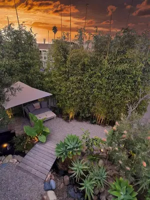 a garden with a wooden walkway and a bench at Channel Islands Beach Retreat in Oxnard