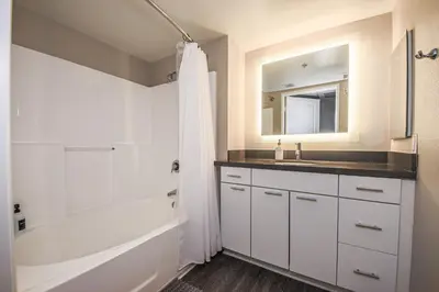 a bathroom with a white tub and a sink and a mirror at Sunny 2BDR in SM Pool & Gym - 5 min to the beach! in Los Angeles