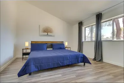 a white bedroom with a blue bed and windows at Modern 4-BR near China Lake in Ridgecrest