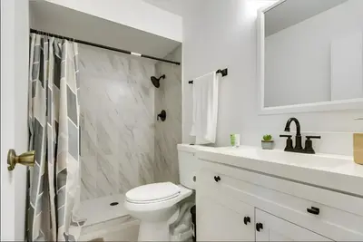 a white bathroom with a toilet and a sink at Modern 4-BR near China Lake in Ridgecrest