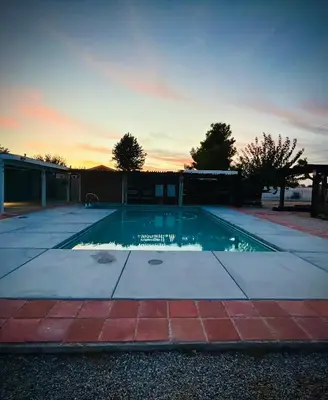 a swimming pool with a sunset in the background at Western style pool home, 4 bedroom and large yard in Apple Valley