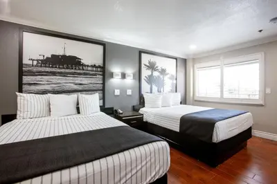 a hotel room with two beds and a painting on the wall at Elev8 Hotel Los Angeles, LAX in Inglewood