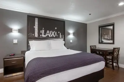 a bedroom with a large bed with a desk and a table at Elev8 Hotel Los Angeles, LAX in Inglewood