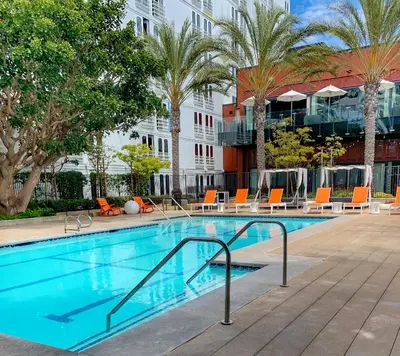 a swimming pool with chairs and a building at Aloft El Segundo - Los Angeles Airport in El Segundo