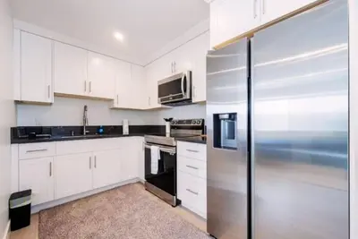 a kitchen with white cabinets and a stainless steel refrigerator at Prestige Studio Haven at Burbank in Burbank