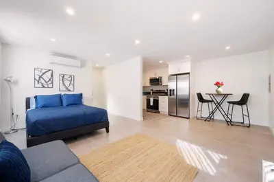a living room with a blue bed and a kitchen at Prestige Studio Haven at Burbank in Burbank