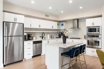 a kitchen with white cabinets and a stainless steel refrigerator at Spinel Stay - Charming 2BR Retreat Zen Garden Views Central in Los Angeles