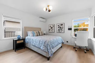 a bedroom with a bed and a desk and two windows at Cozy 3BR in San Gabriel in San Gabriel