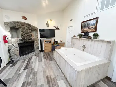 a large bathroom with a large tub and a stone fireplace at Pine Knot Guest Ranch in Big Bear Lake