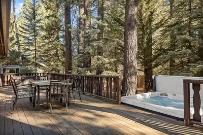 a deck with a table and a hot tub at Nest and Needles in Big Bear Lake