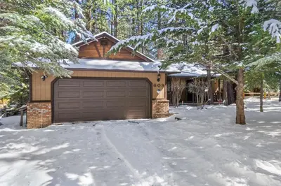 a house with a garage in the snow at Nest and Needles in Big Bear Lake