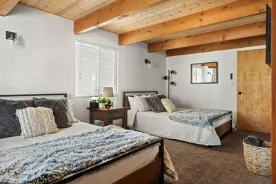 two beds in a bedroom with wooden ceilings at Wild Heart Cabin in Big Bear Lake