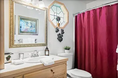 a bathroom with a sink and a red shower curtain at Boulder Bay Waterfront Breeze in Big Bear Lake