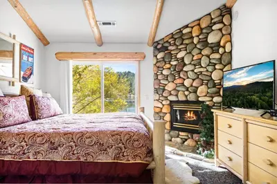 a bedroom with a stone wall with a bed and a fireplace at Boulder Bay Waterfront Breeze in Big Bear Lake