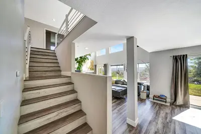 a staircase in a home with white walls and wooden floors at Stunning Hilltop 5BR With View And Hot Tub! in Lakeside Park