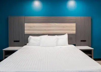 a bedroom with a large white bed with a blue wall at La Mirage Inn - Long Beach in Long Beach