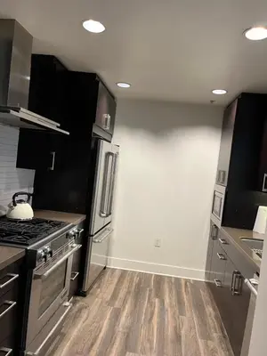 a kitchen with stainless steel appliances and wooden floors at NoHo in Los Angeles
