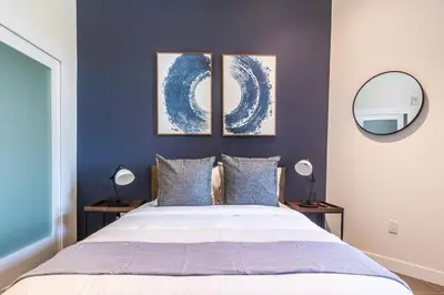 a bedroom with a bed with three paintings on the wall at DTLA 2BR Rooftop Jacuzzi & Sunset Views in Los Angeles
