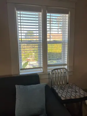 a living room with two large windows and a chair at Cozy One Bedroom Apartment in Los Angeles