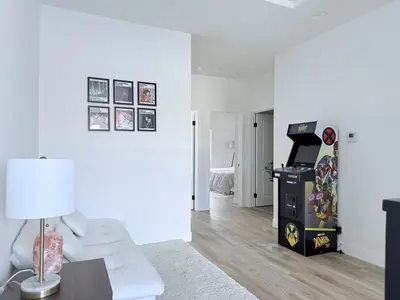 a living room with a video game machine in a room at Modern Family Haven - Minutes from Disney Magic-OC in Midway City