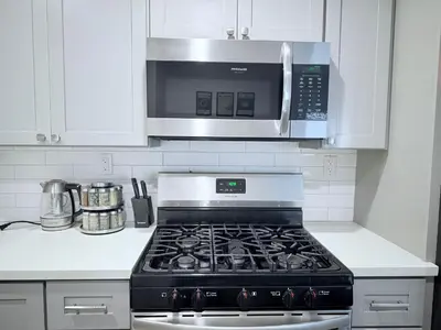 a kitchen with a stove and a microwave at Modern Family Haven - Minutes from Disney Magic-OC in Midway City