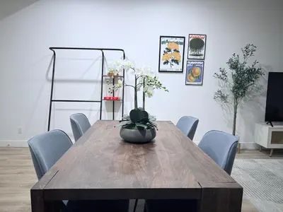 a dining room table with a vase of flowers on it at Modern Family Haven - Minutes from Disney Magic-OC in Midway City