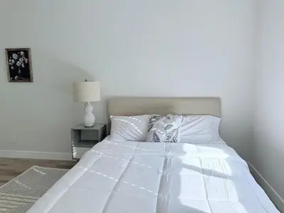 a white bed in a white bedroom with a lamp at Modern Family Haven - Minutes from Disney Magic-OC in Midway City