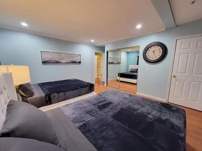 a bedroom with two beds and a clock on the wall at 3 bedroom guest suite first floor unit with nice patio area right next to the MrC Hotel 10 minutes from Rodeo Drive Washer Dryer WIFI and more in Los Angeles