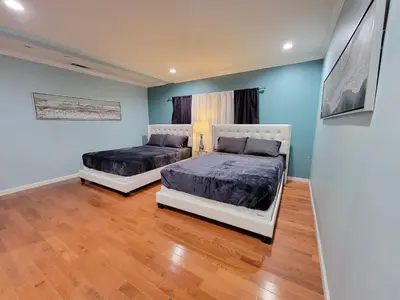 two beds in a room with blue walls and wooden floors at 3 bedroom guest suite first floor unit with nice patio area right next to the MrC Hotel 10 minutes from Rodeo Drive Washer Dryer WIFI and more in Los Angeles