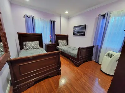 two beds in a room with blue curtains at 3 bedroom guest suite first floor unit with nice patio area right next to the MrC Hotel 10 minutes from Rodeo Drive Washer Dryer WIFI and more in Los Angeles