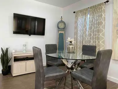 a dining room with a glass table and a clock at Serene Sherman Oaks Cottage with Outdoor Space in Los Angeles