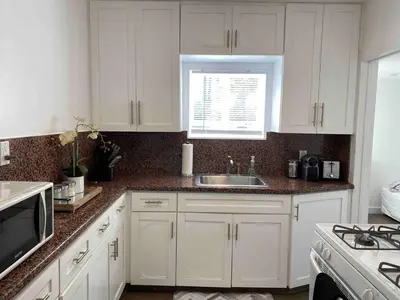 a kitchen with white cabinets and a sink and a window at Serene Sherman Oaks Cottage with Outdoor Space in Los Angeles