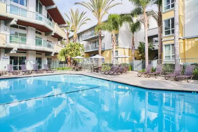a swimming pool in front of a building with palm trees at Smoky Quartz - Marina View Spacious 3BR near Yacht Club in Los Angeles