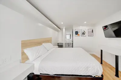 a white bedroom with a bed and a tv at Casablanca Inn in Bell
