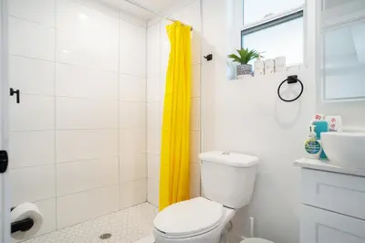 a bathroom with a white toilet and a yellow shower curtain at Cozy Urban Retreat near Downtown LA & USC - Private room with shared Living room and kitchen in Los Angeles