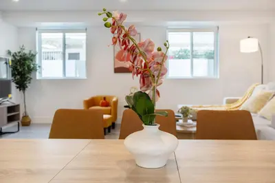 a white vase with flowers on a table in a living room at Cozy Urban Retreat near Downtown LA & USC - Private room with shared Living room and kitchen in Los Angeles