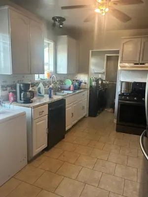 a kitchen with white cabinets and a tile floor at Cheryls home in Inglewood