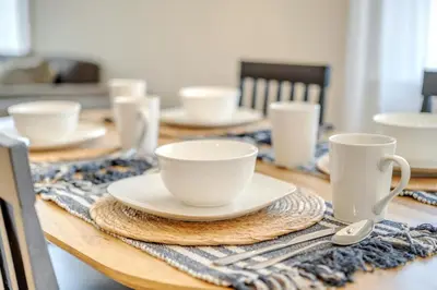 a wooden table with white cups and plates on it at Centrally Located Charming LA Home with Food Scenes in Monterey Park
