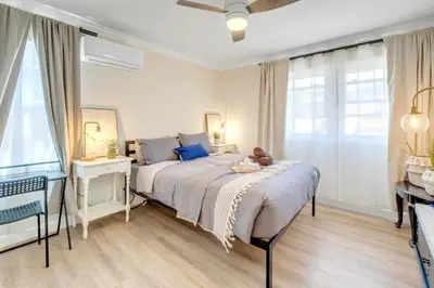 a bedroom with a bed and a desk and windows at Centrally Located Charming LA Home with Food Scenes in Monterey Park