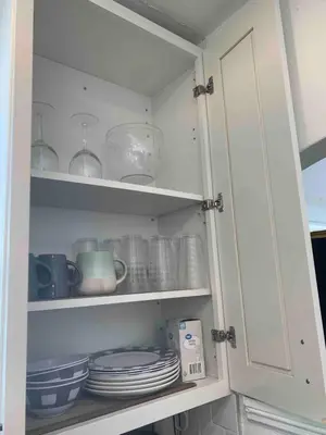 a white cabinet with plates and dishes in it at Cozy Spacious, free parking, near it all in South Gate