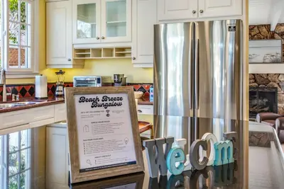 a kitchen with a stainless steel refrigerator with a sign at Beach Breeze Bungalow 1 Miles To Beach Cozy in Redondo Beach