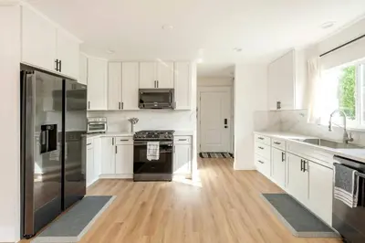 a kitchen with white cabinets and a stainless steel refrigerator at Stylish Gated Retreat in East Hollywood with Parking in Los Angeles