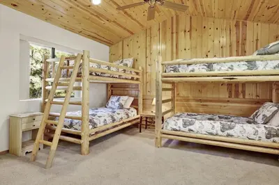 two bunk beds in a room with wooden walls at Eagle Point Lake House by Big Bear Vacations in Big Bear Lake