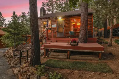 a cabin in the woods with a bench in front at The Nest on Towne Trail by Big Bear Vacations in Big Bear Lake