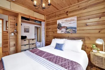 a bedroom with a bed in a room with wooden walls at The Nest on Towne Trail by Big Bear Vacations in Big Bear Lake