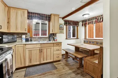 a kitchen with wooden cabinets and a wooden table at Green Squirrel Chateau by Big Bear Vacations in Big Bear Lake