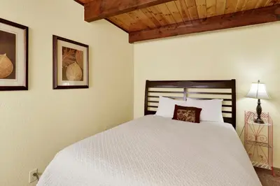 a bedroom with a white bed with a wooden ceiling at Buttercup Snow Summit Condo by Big Bear Vacations in Big Bear Lake