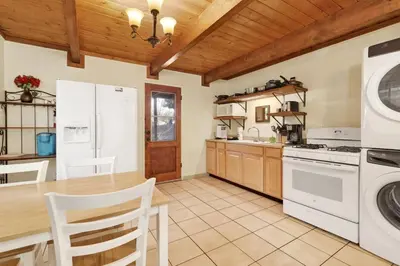a kitchen with a table and a washer and dryer at Aeroplane Gambrel Chalet- Adorable Airport Retreat Cottage in Big Bear City