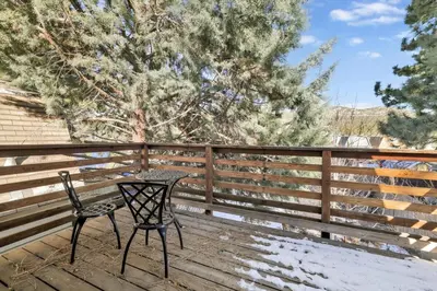a table and chairs on a deck with a fence at Aeroplane Gambrel Chalet- Adorable Airport Retreat Cottage in Big Bear City