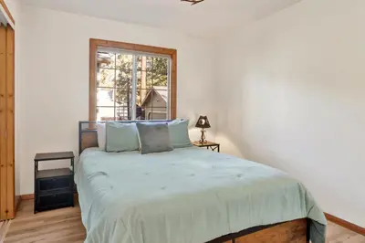 a bedroom with a large bed with blue pillows at Oriole House- Walk to Lake Chalet w/ Hot Tub in Big Bear Lake